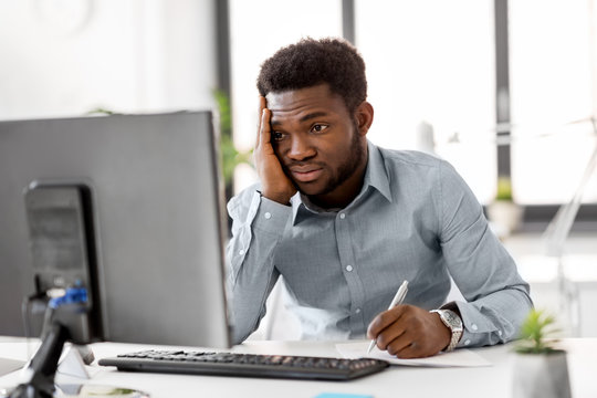 business, people, paperwork and technology concept - stressed african american businessman with computer and papers working at office