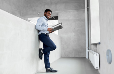 business, people and corporate concept - smiling african american businessman with folder at office