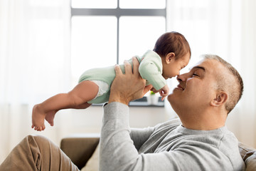 family, fatherhood and people concept - happy father with little baby boy sitting on sofa at home