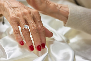 Female aged hand with diamond. Senior woman hand with red manicure wearing golden ring with diamond.