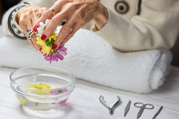 Spa treatment for female hands. Old woman beautiful hands with red manicure receiving spa procedure. Womens skin care and treatment.