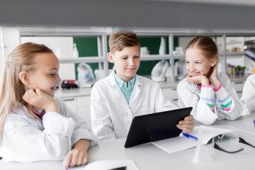 education, science and technology concept - kids with tablet pc computer studying biology or chemistry at school laboratory