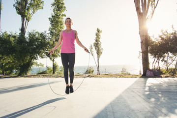  A beautiful athletic girl is jumping rope in the summer on a hot morning.