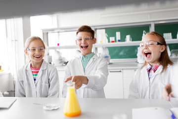 education, science, chemistry and children concept - kids or students with test tube making experiment at school laboratory