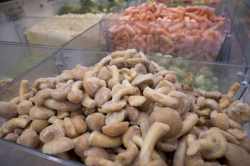 Assortment of frozen vegetables and mushrooms in the supermarket fridge
