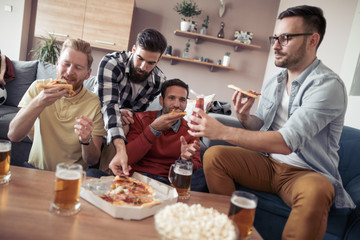 Male friends playing video games and eat pizza