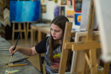 Cute little girl painting a picture in home studio