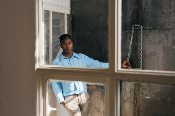 African-American man looking out dirty window