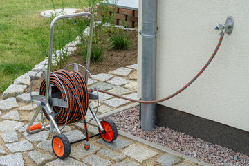 water hose and water tap at the wall of a house - gardening