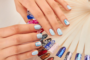 Obraz na płótnie Canvas Well-groomed hands with beautiful manicure. Young woman hands with winter design manicure holding nail art design samples. Nails beauty salon.