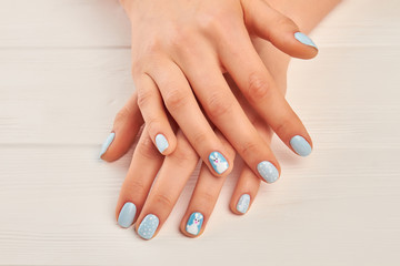 Female hands with winter manicure. Well-groomed woman hands with cute winter design manicure. Manicured hands close up.