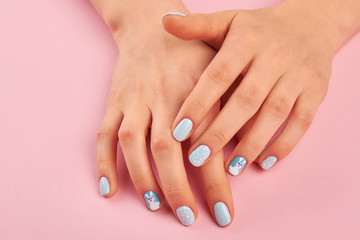 Trendy winter design manicure. Woman hands with cute winter design manicure on pink background. Nail art fashion style.