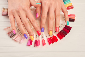Hands with summer multicolored nails. Samples of various hand painted fingernail designs and manicured hands. Stylish summer manicure.