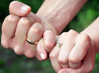 The hands of the husband and wife are linked by the little fingers