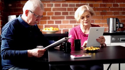 Mature couple sitting with tablet and newspapers in the kitchen
- Powered by Adobe