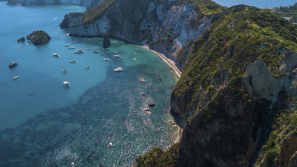 Fototapeta na wymiar Aerial view of Frontone beach in Ponza, in Italy. This is a small bay of an island overlooking the Mediterranean Sea. The beach is full of people.