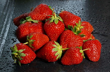 large ripe red strawberry berries on a dark background water drop