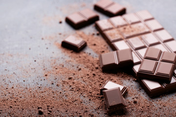 Chocolate pieces with cocoa powder on wooden table