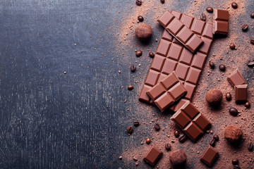 Morceaux de chocolat avec grains de café et poudre de cacao sur table en bois