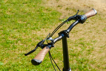 Fototapeta na wymiar the handlebars of the bike. brake handles. Blurred background, bokeh. Green grass. Bicycle element. Nature.