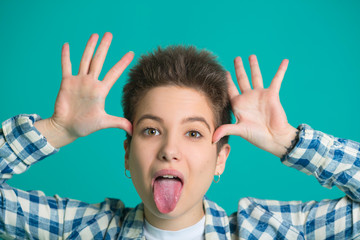 beautiful young girl with short hair in a shirt on a blue background with a fun facial expression...