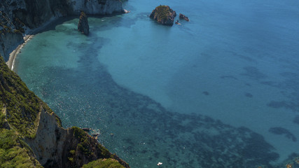 Aerial view of Frontone beach in Ponza, in Italy. This is a small bay of an island overlooking the Mediterranean Sea. The beach is full of people.