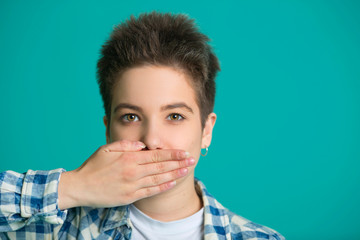 beautiful young girl with a male hairdress on a blue background with a closed mouth