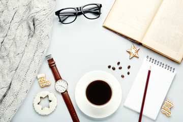 Cup of coffee with notebook, book, glasses and grey sweater