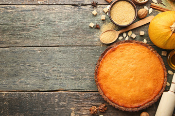 Pumpkin tart with sugar in bowl and seeds on wooden table