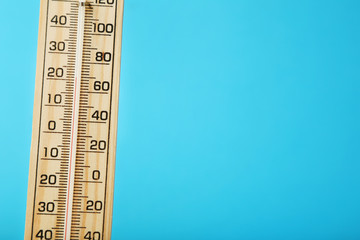 Wooden thermometer on blue background