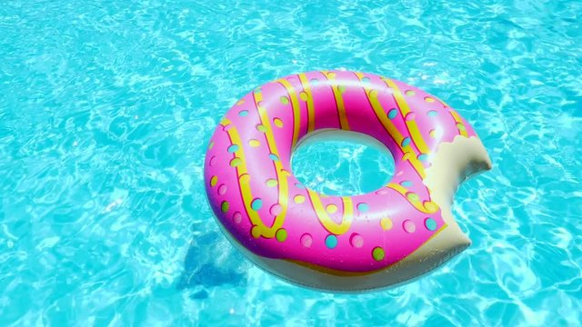 Inflatable Donut pool toy in a blue swimming pool on sunny day