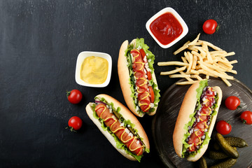 Hot dogs with vegetables and french fries on wooden table