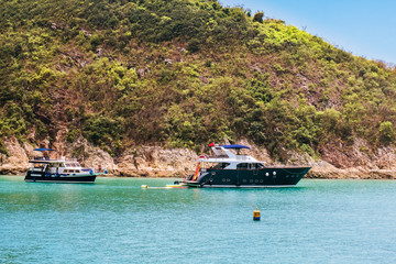 Obraz premium Recreational boats anchoring near small islands. A group of unrecognizable people having fun activities on holidays vacation sea trip. Perfect family getaway. Travel and lifestyle concept.