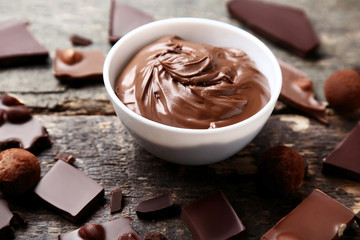 Melted chocolate in bowl with cocoa balls on wooden table