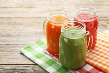 Vegetables smoothie in jars on grey wooden table