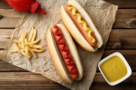 Hot dogs with mustard and ketchup on wooden table