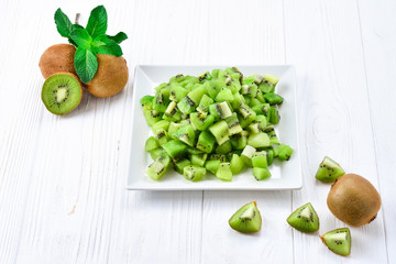 Freshly sliced kiwi fruit with whole kiwis in background.