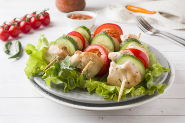 Traditional Turkey chicken kebab meat with tomatoes, cucumber and fresh herbs on a plate.
