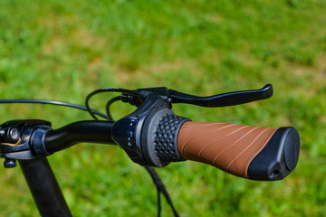 the handlebars of the bike. brake handles. Blurred background, bokeh. Green grass. Bicycle element....