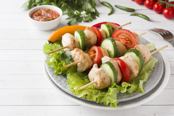 Traditional Turkey chicken kebab meat with tomatoes, cucumber and fresh herbs on a plate.