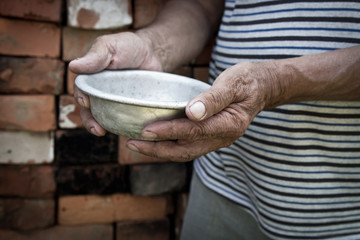 The poor old man's hands hold an empty bowl. The concept of hunger or poverty. Selective focus....