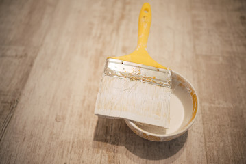 Open can of white paint with brush