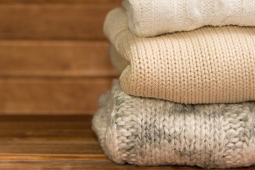 Fototapeta na wymiar Stack of cozy knitted warm sweater ,wooden background