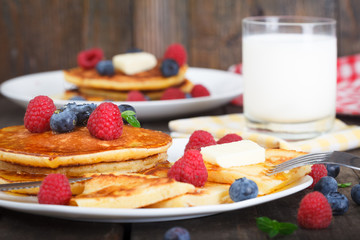 Classic american breakfast, homemade  pancakes with fresh berries, honey and glass of milk