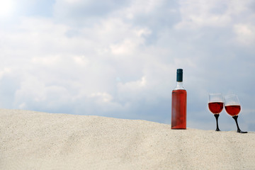 Butelka czerwonego wina i dwa kieliszki na piaszczystej wydmie. © Stanisław Błachowicz