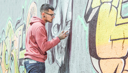 Obraz premium Uliczny artysta graffiti malujący kolorowym sprayem Graffiti z ciemną czaszką potwora na ścianie w mieście - Koncepcja miejskiej, lifestyle'owej sztuki ulicznej - Główny nacisk na jego rękę