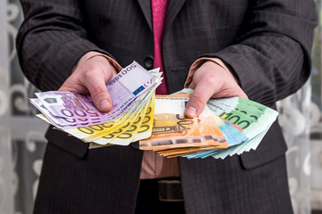 Businessman in suit showing earnings, euro banknotes