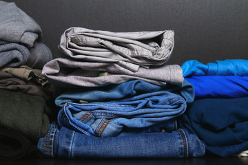 Neat stacks of different clothes lie on a shelf in the closet.