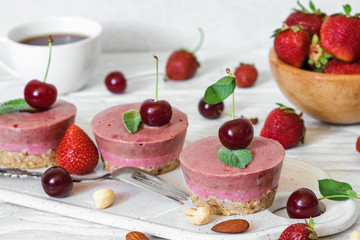 healthy breakfast. raw strawberry and cherry cakes with fresh berries, mint, nuts and coffee cup