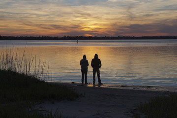 Fototapeta na wymiar Mindful Couple Watch a Colorful Sunset Over the Bay
